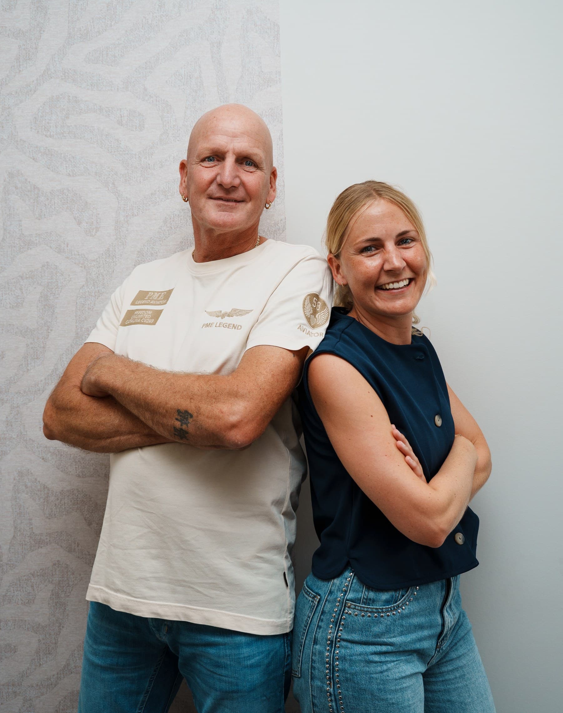 Leen Fischer en zijn dochter Nikki van HUISS styling, rug aan rug tegen een behangen wand