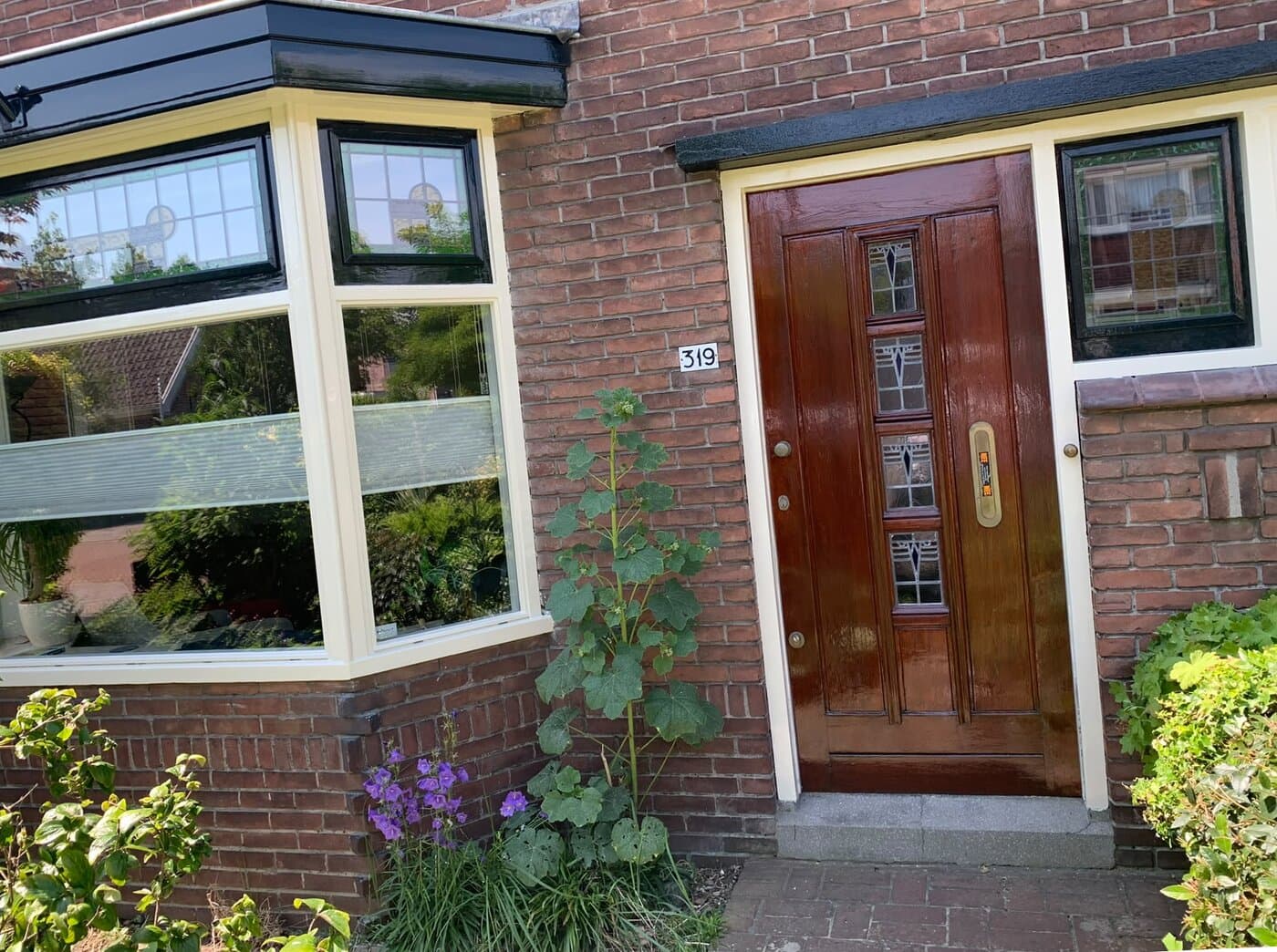 Erker met glas in lood naast een gelakte houten voordeur