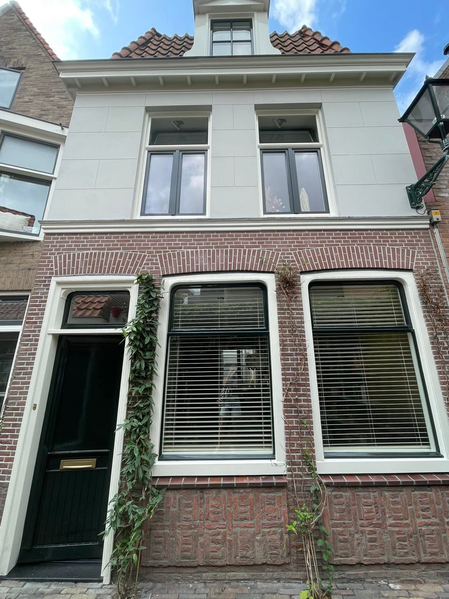Gerenoveerde Alkmaarse gevel met wit gestucte bovenverdieping en pas geschilderde kozijnen
