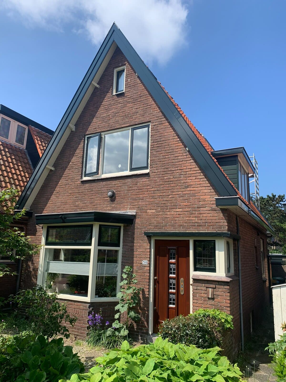 Vrijstaande woning met puntgevel, pas geschilderde kozijnen en een houten voordeur