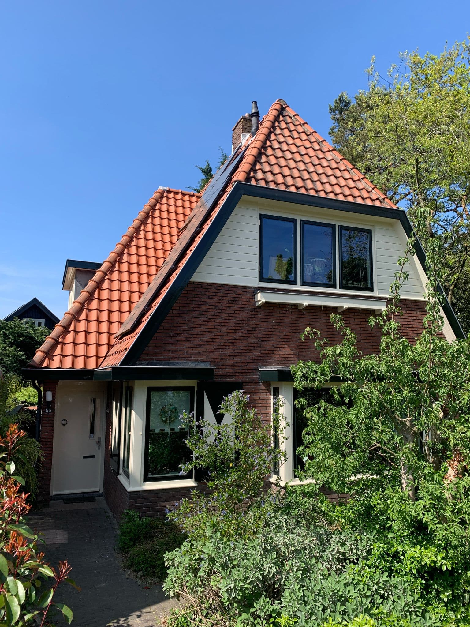 Vrijstaande woning met een pas geschilderde witte dakkapel, kozijnen en voordeur