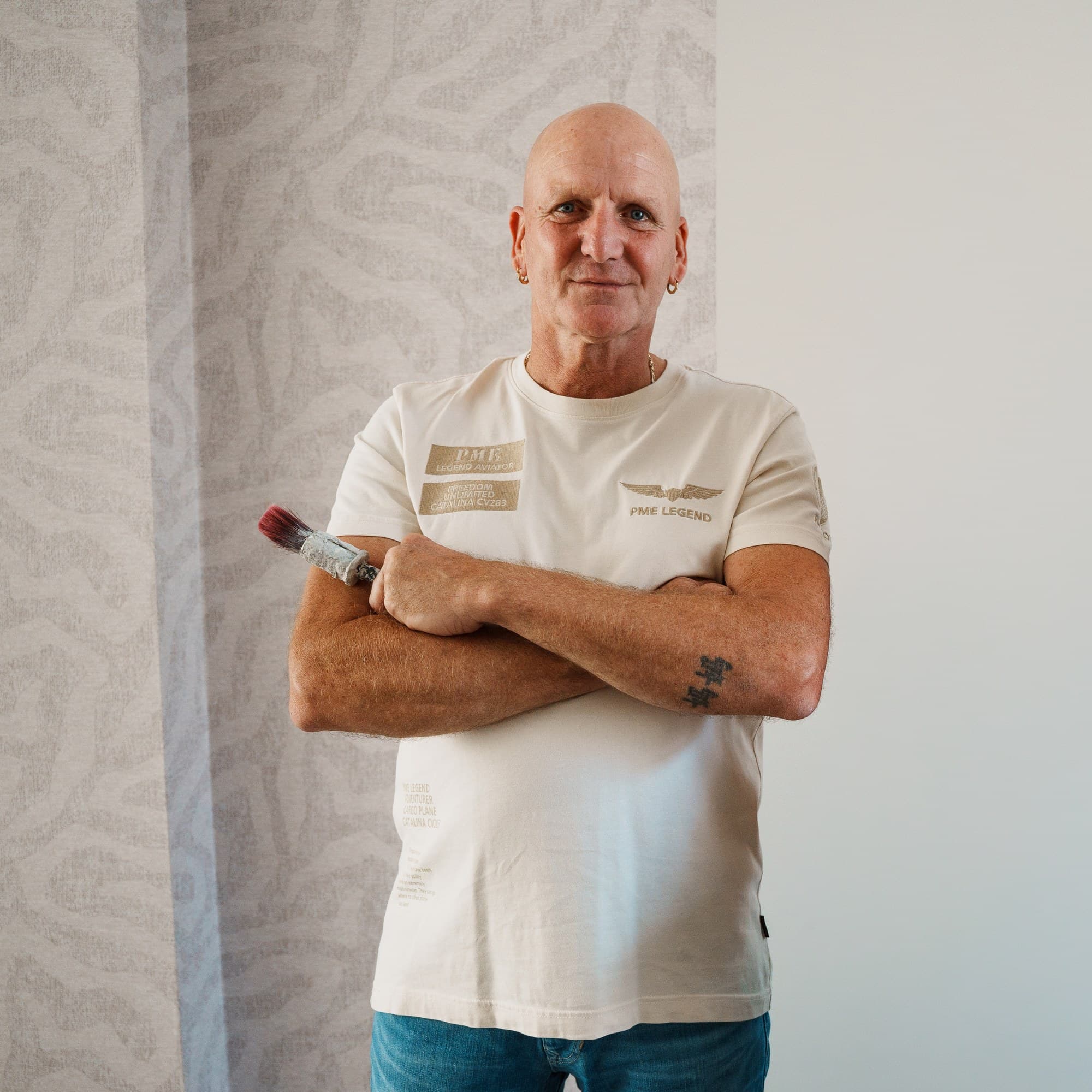 Leen Fischer in bedrijfskleding tegen een houten wand
