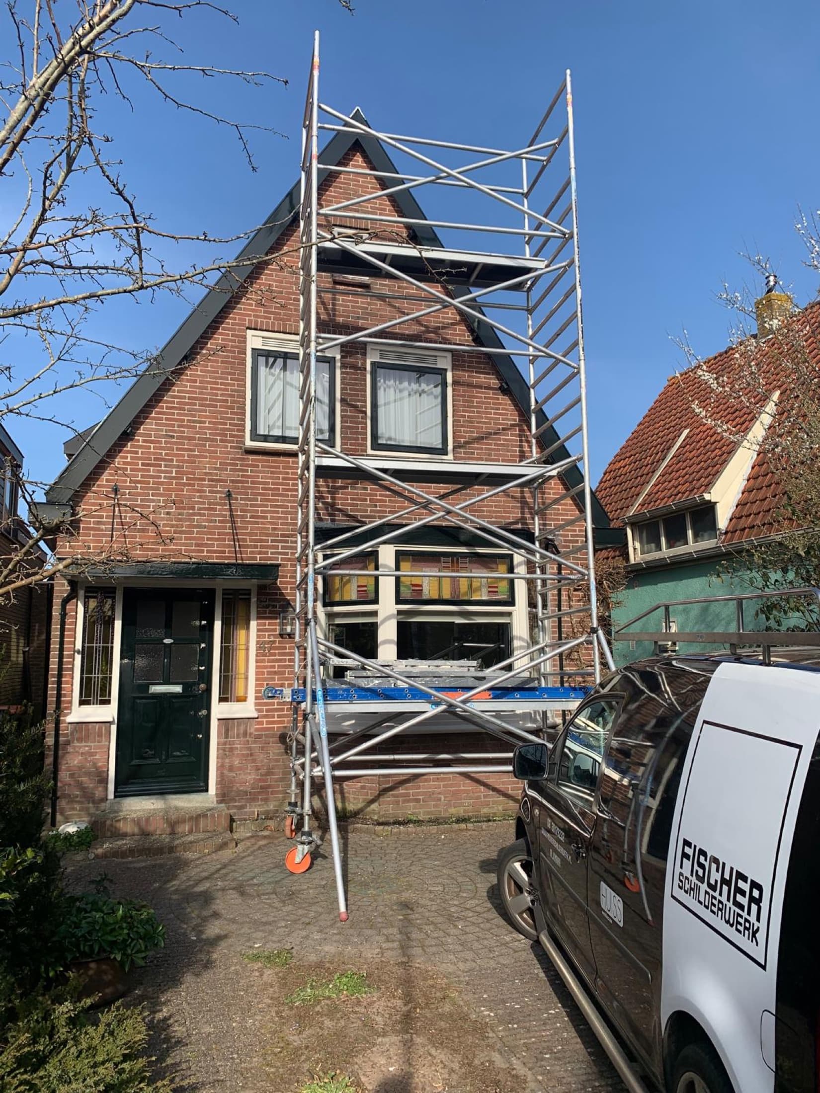 Steiger tegen een woning waar het buitenschilderwerk wordt uitgevoerd