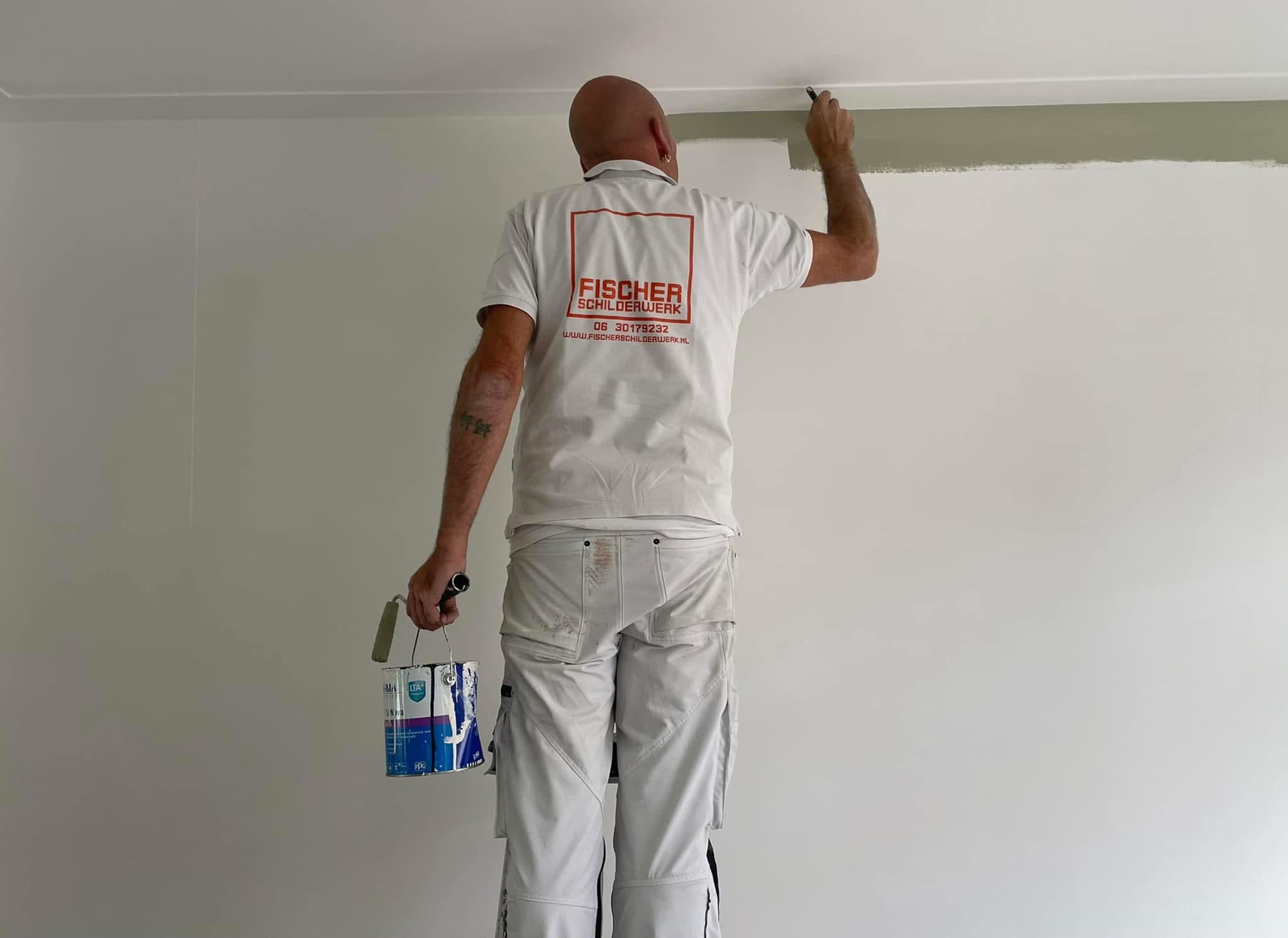 Leen Fischer trekt met een kwast een strakke strook langs het plafond