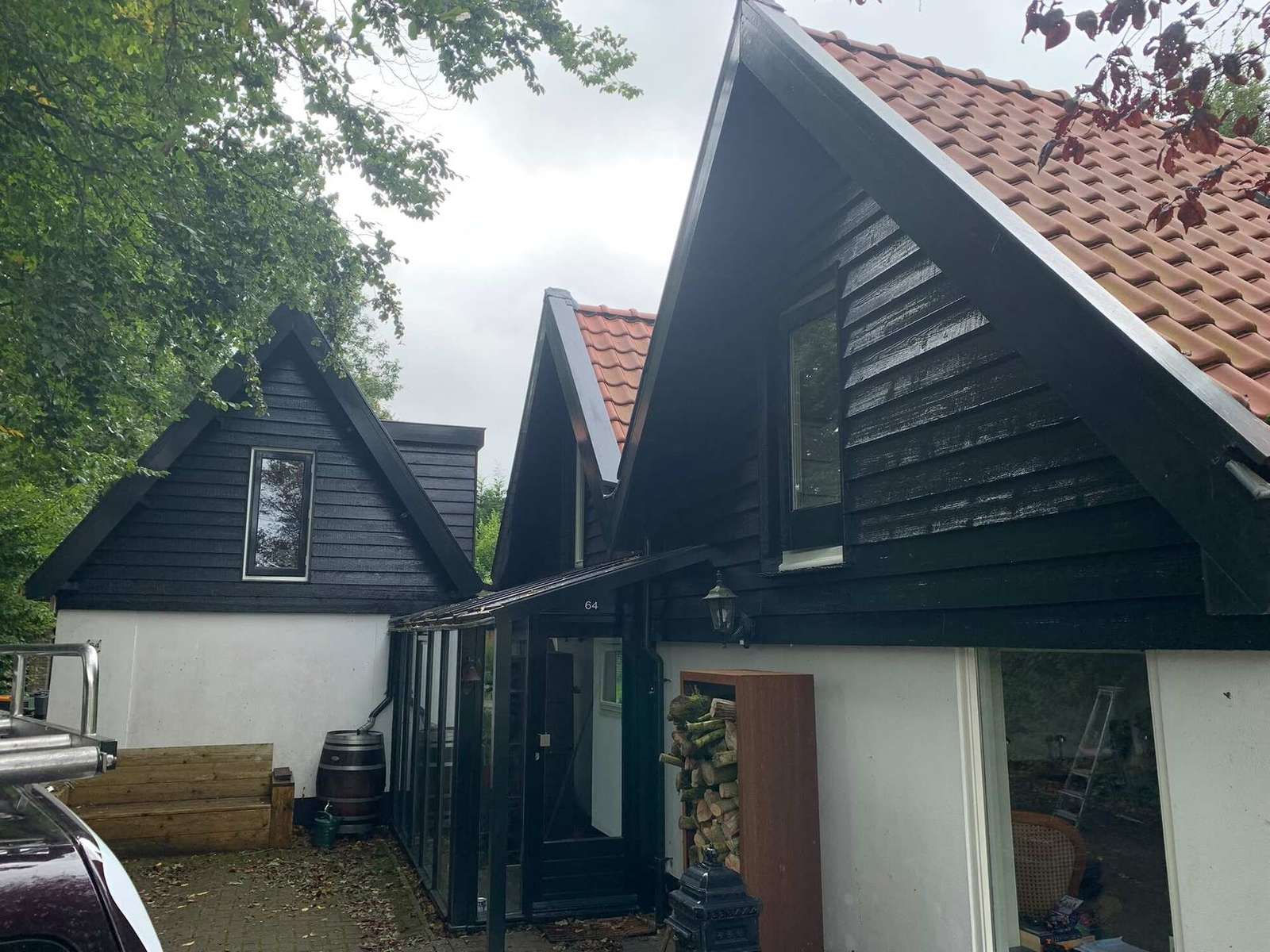 Vrijstaande woning met donkere gevelbetimmering tussen de bomen in Heiloo